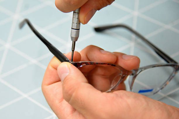 Optician repairing and fixing eye glasses with screwdriver, close-up